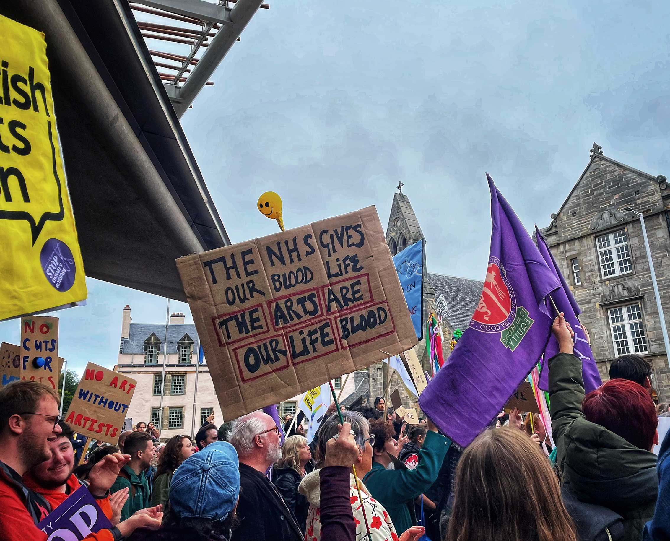 A crowd of people protest the Scottish Government’s cuts to arts funding. 